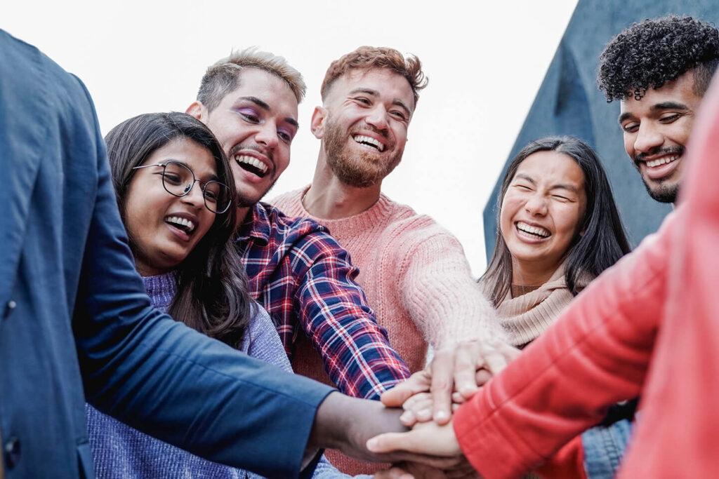 Group of five younger adults putting their hands together 