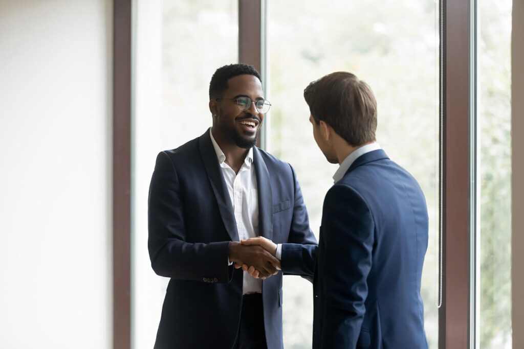 Two business men shaking hands in front of a window after opening a business checking account