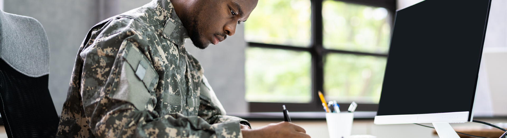 Man in military uniform applying for a military checking account online