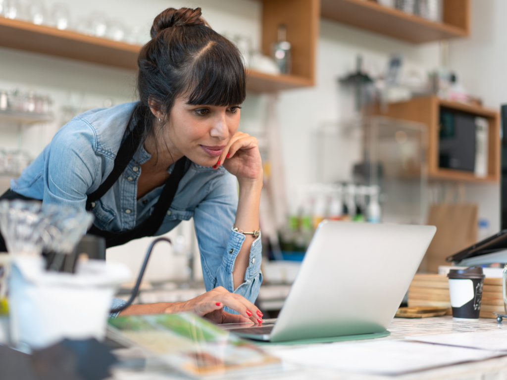 female coffee shop owner reading on her computer about how to manage your checking account