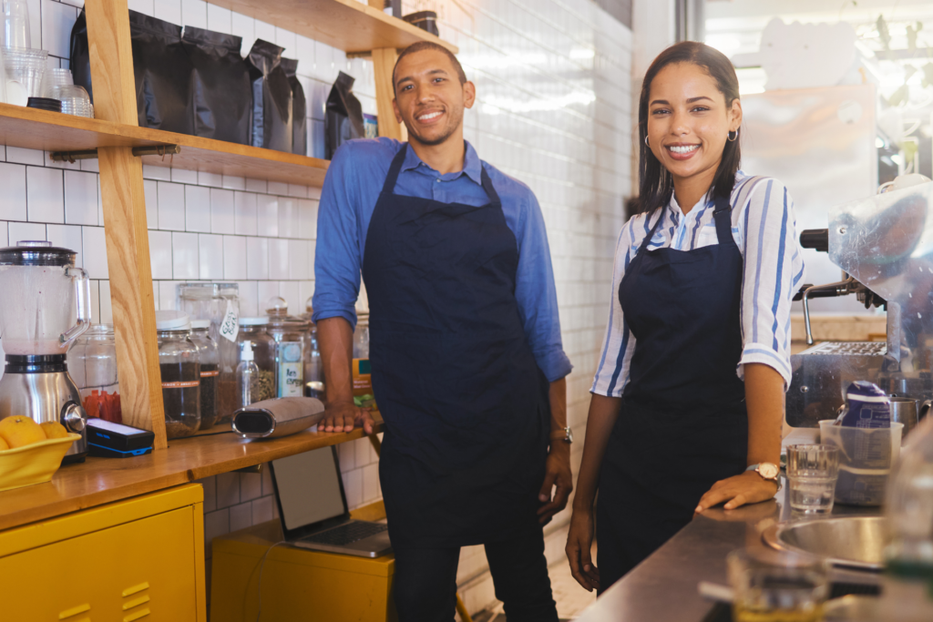 owners of a local coffee shop and cafe stand behind the counter of a space that they funded with commercial lending from quaint oak bank and have a business checking account