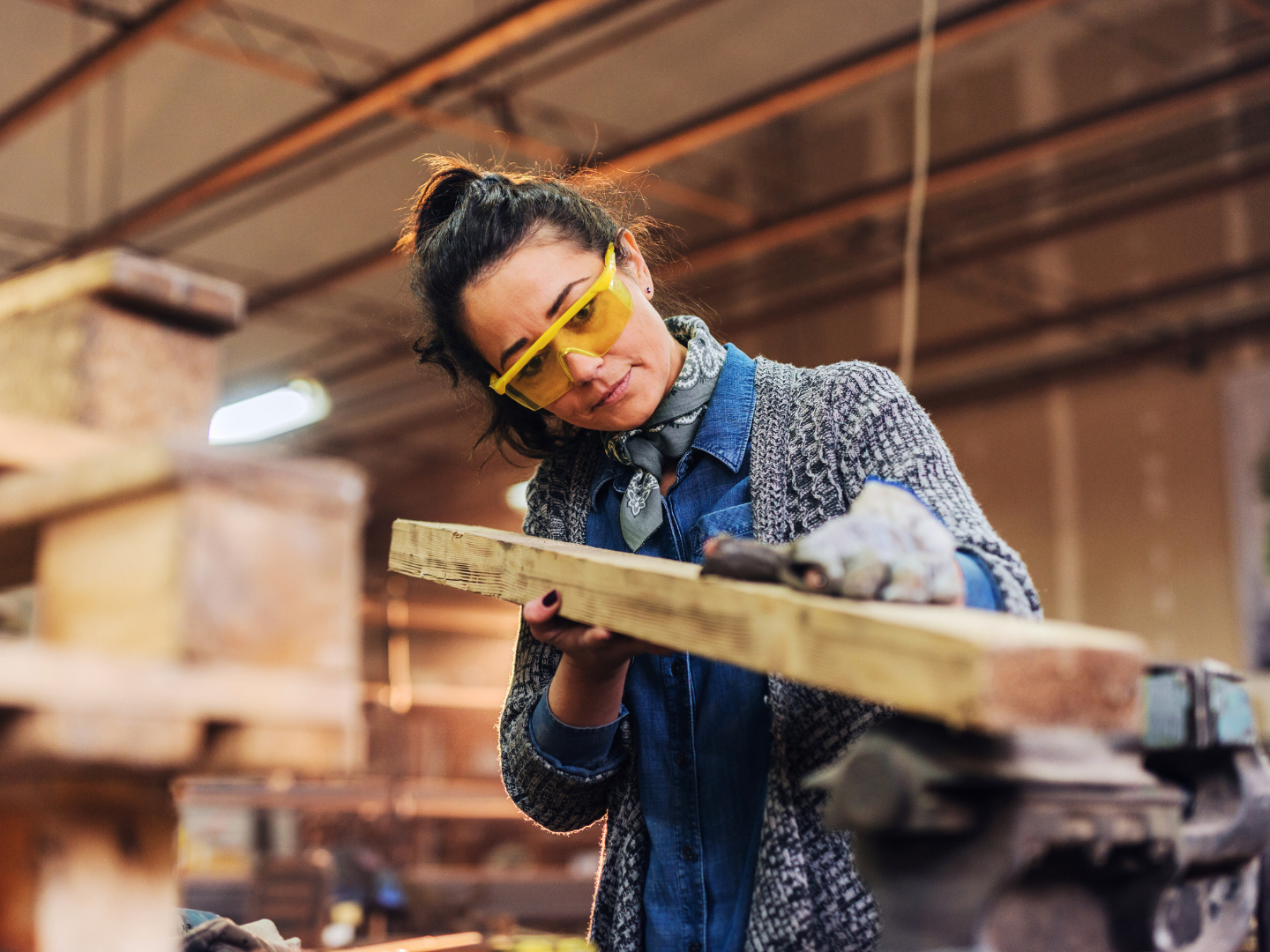 a female tradesperson specializing in carpentry works in her shop on a project using equipment financed with capital for skilled trades