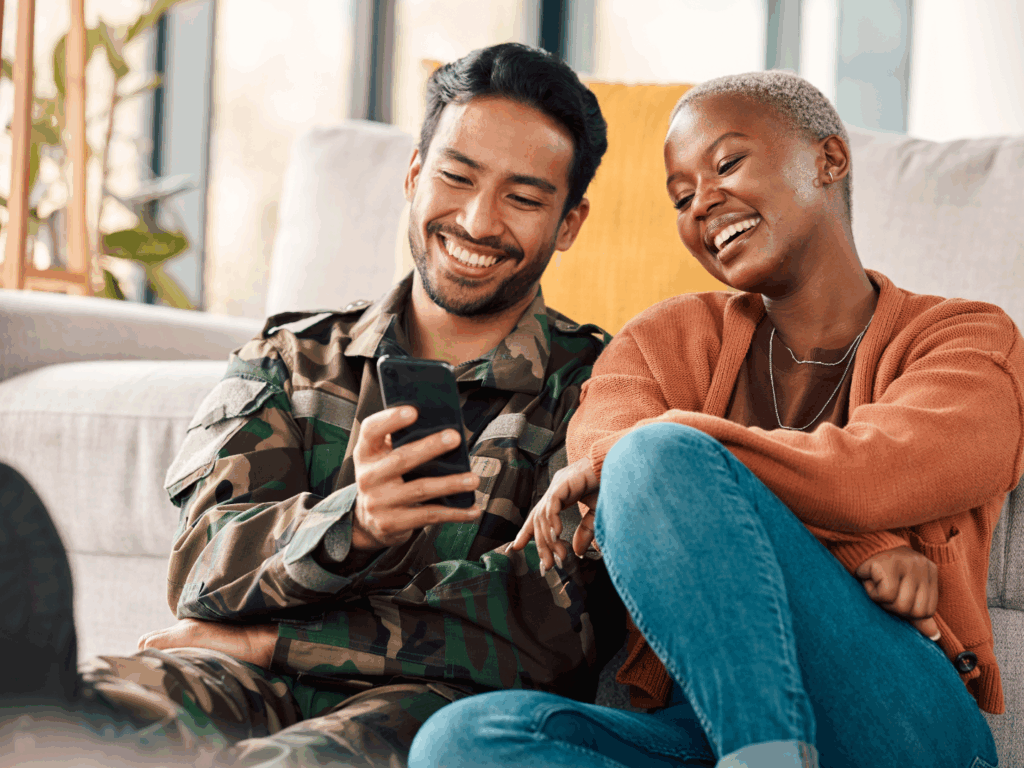 Una pareja revisa sus opciones con una cuenta bancaria militar en un teléfono celular.