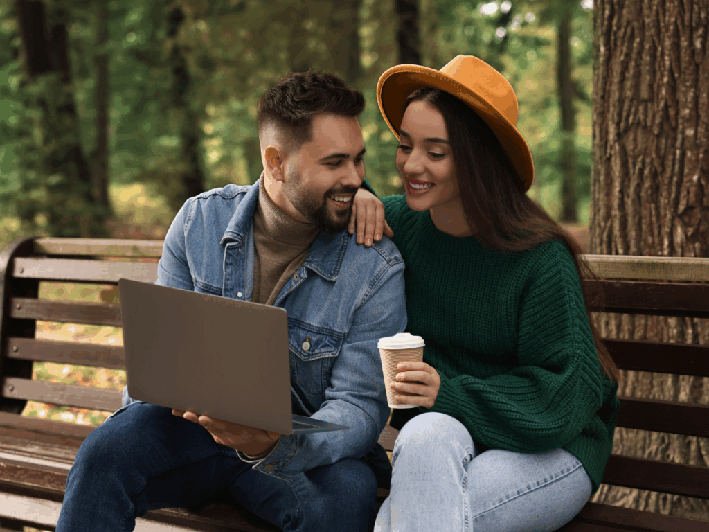 a couple reviewing their personal CD account options together on their laptop while sitting under an oak tree