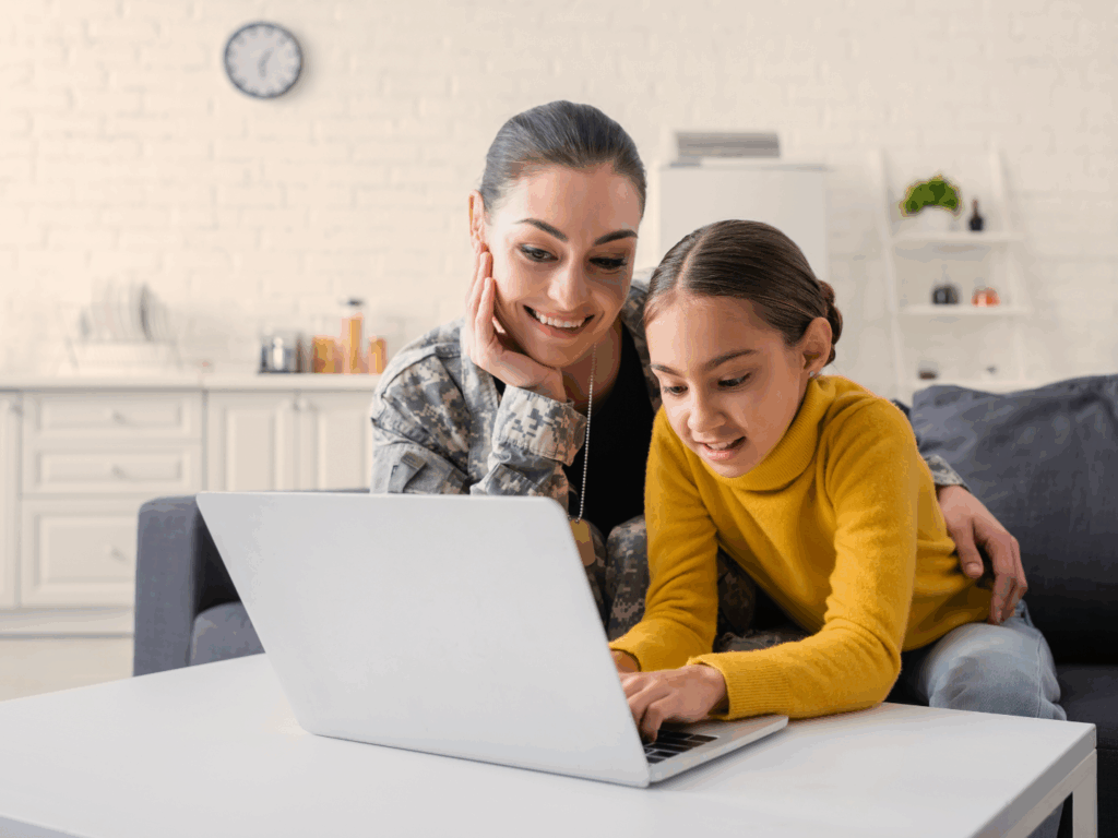 Una madre militar en la computadora con su hija revisando opciones de cuentas bancarias militares