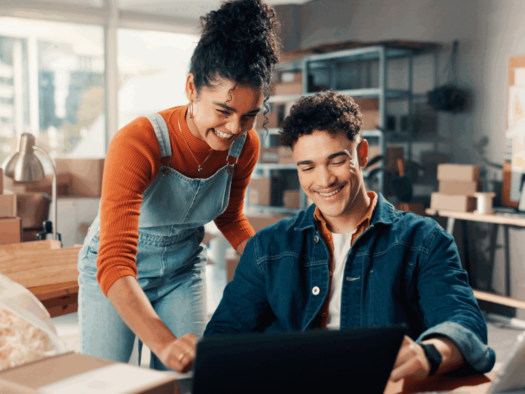 the owner of a small manufacturing company looks at his sba preferred lender options on his computer with his employee