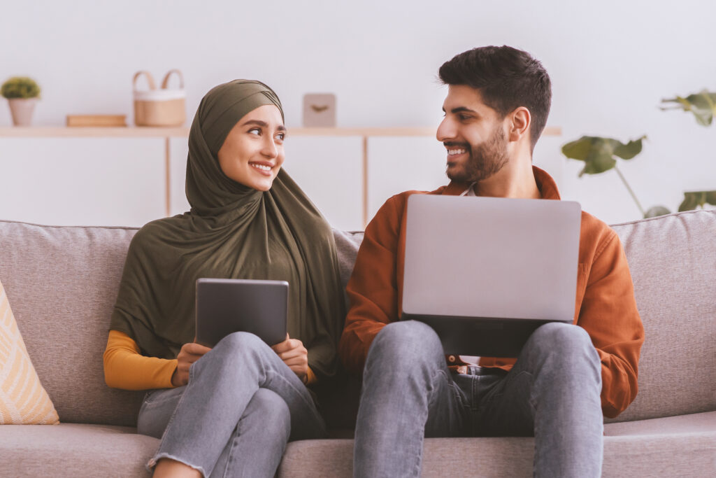 Middle Eastern Couple Using Laptop to look at quaint oak bank certificate of deposits